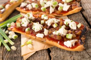 Pizza mit Schinkenwürfeln, Feta und Gurkensalat