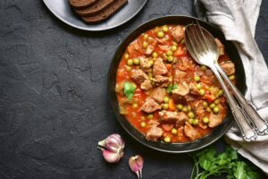 Kalbseintopf mit Erbsen, Paprika und Möhren in Tomatensauce