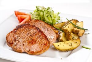 Schweinesteak mit Ofenkartoffeln und Tomaten-Gurkensalat