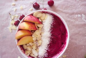 Smoothie-Bowl mit Himbeeren, Kirschen, Nektarine, Mandeln und Kokos